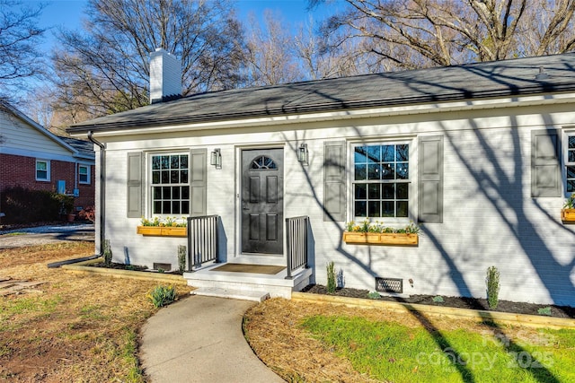 property entrance featuring brick siding, crawl space, and a chimney