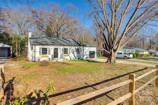 single story home featuring concrete driveway, a chimney, a front yard, and fence