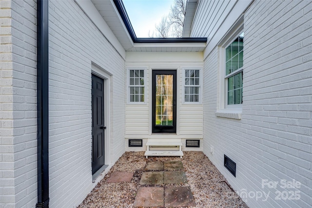 property entrance with crawl space and brick siding