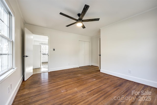 interior space with ceiling fan, baseboards, dark wood-style flooring, and ornamental molding