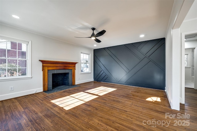 unfurnished living room with dark wood-style flooring, a fireplace with flush hearth, a ceiling fan, baseboards, and crown molding