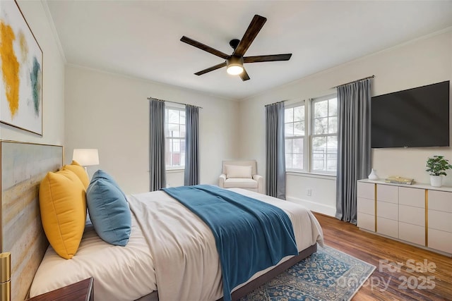 bedroom featuring baseboards, ornamental molding, dark wood finished floors, and a ceiling fan