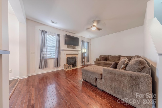 living room with a fireplace with flush hearth, dark wood-style flooring, visible vents, and a ceiling fan