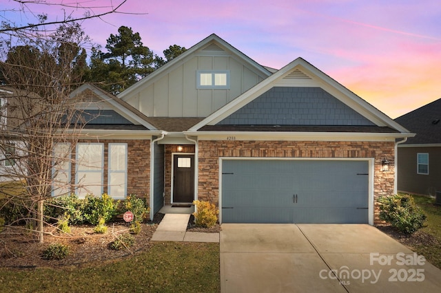 view of front of property with a garage, driveway, stone siding, roof with shingles, and board and batten siding