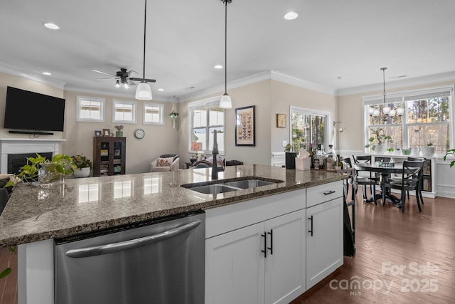 kitchen with open floor plan, stainless steel dishwasher, a fireplace, and a sink