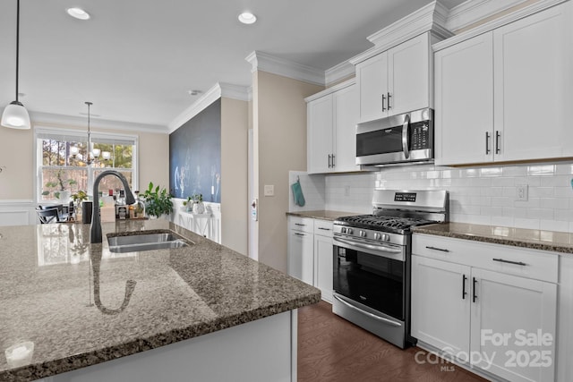 kitchen featuring stainless steel appliances, a sink, white cabinets, dark stone counters, and crown molding