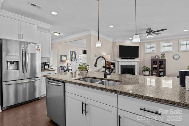 kitchen with visible vents, open floor plan, stainless steel appliances, crown molding, and a sink