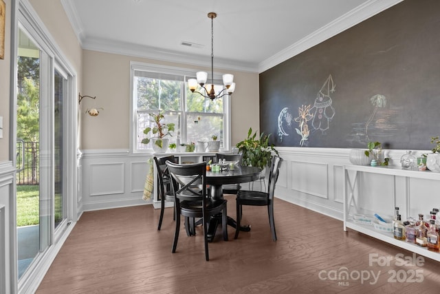 dining area featuring visible vents, wainscoting, ornamental molding, dark wood-style flooring, and an inviting chandelier