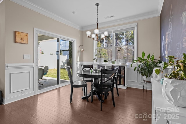 dining room featuring a notable chandelier, dark wood-type flooring, visible vents, and crown molding