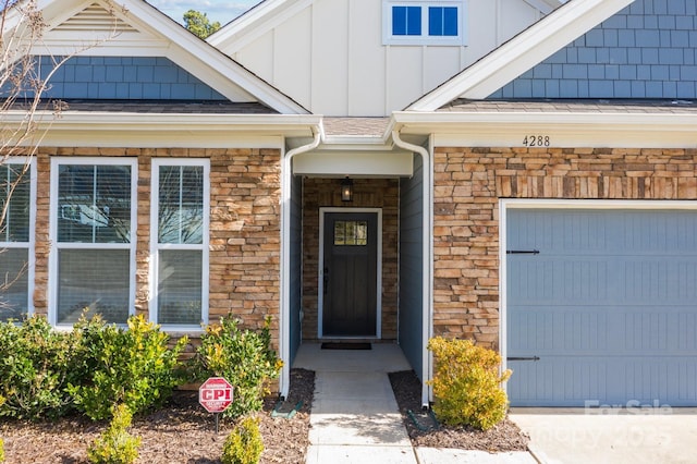 view of exterior entry featuring board and batten siding, stone siding, and a garage