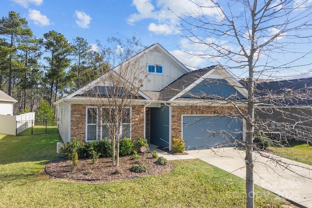 view of front of property with an attached garage, fence, stone siding, driveway, and a front yard