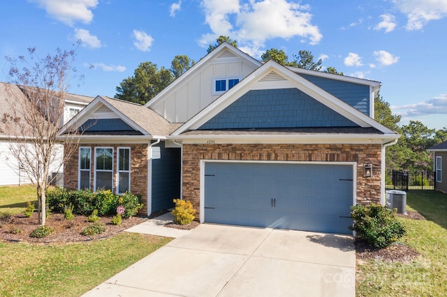 craftsman-style home with an attached garage, board and batten siding, cooling unit, stone siding, and driveway