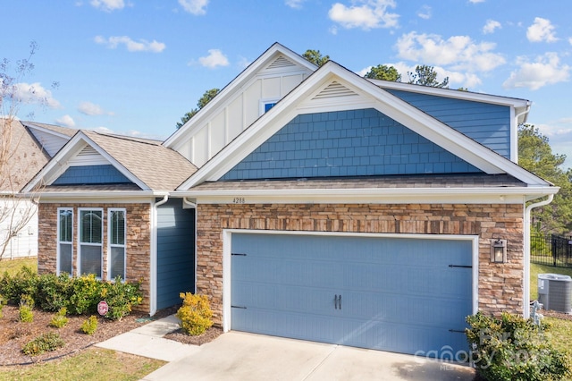 view of front of property with stone siding, central AC, an attached garage, and concrete driveway