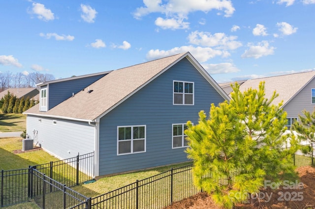 exterior space with a shingled roof, a lawn, cooling unit, and a fenced backyard