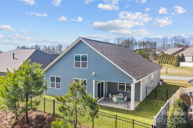 rear view of house with a yard, a shingled roof, a patio area, and a fenced backyard