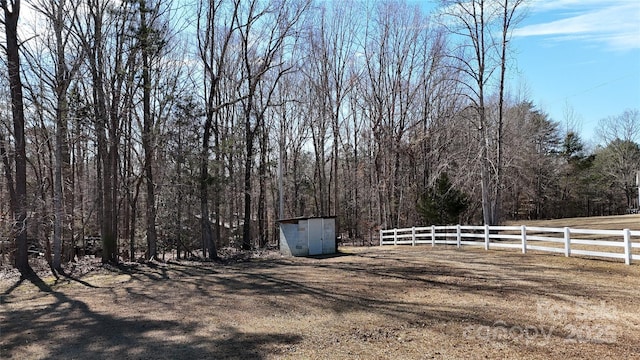 view of yard featuring fence, a storage unit, and an outdoor structure