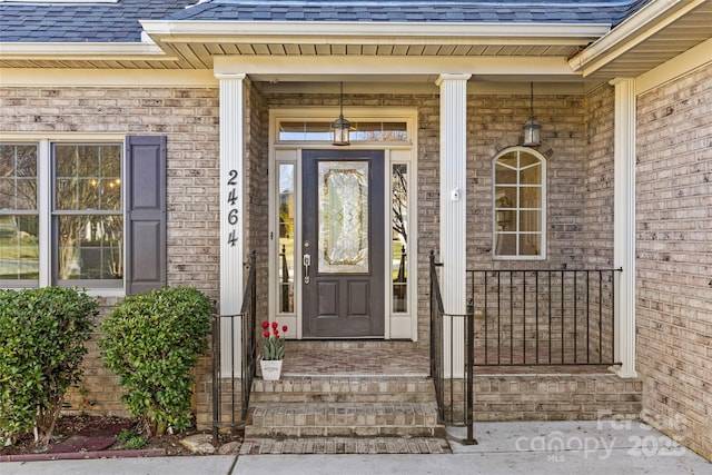 entrance to property with brick siding and roof with shingles