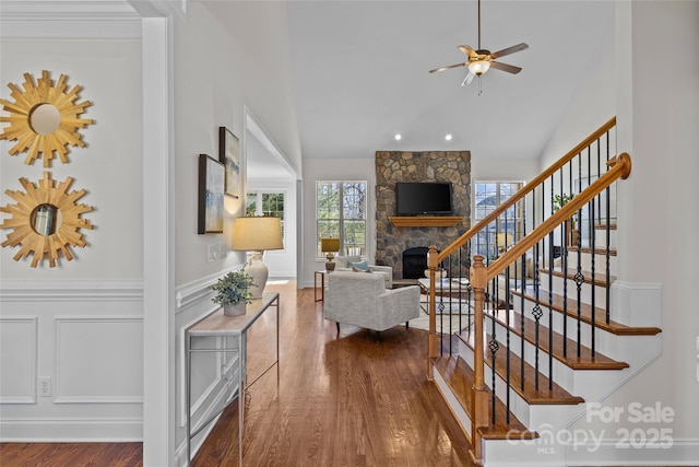 living area with stairs, a fireplace, wood finished floors, and a decorative wall