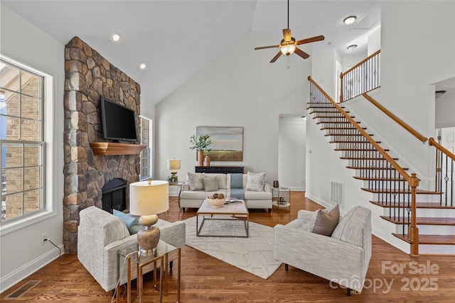 living area with stairs, a fireplace, visible vents, and wood finished floors