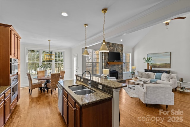 kitchen featuring crown molding, a stone fireplace, a sink, and wood finished floors