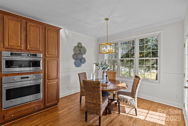 dining space featuring ornamental molding, a notable chandelier, baseboards, and wood finished floors