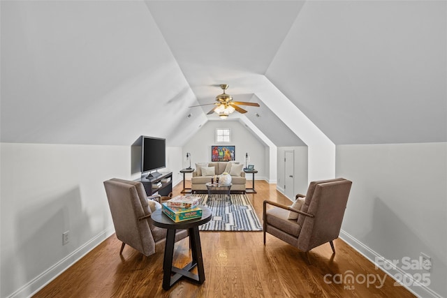 sitting room with a ceiling fan, lofted ceiling, baseboards, and wood finished floors