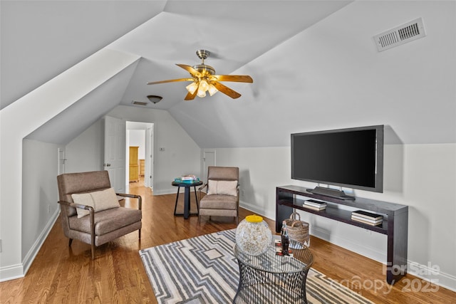 living area with lofted ceiling, wood finished floors, visible vents, baseboards, and a ceiling fan