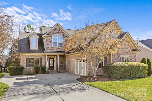 view of front of property featuring a shingled roof, concrete driveway, stone siding, a front lawn, and brick siding