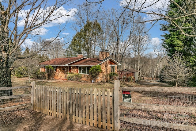 view of front of home with brick siding, a fenced front yard, and a chimney