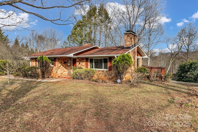 view of front of house featuring brick siding, a chimney, and a front lawn