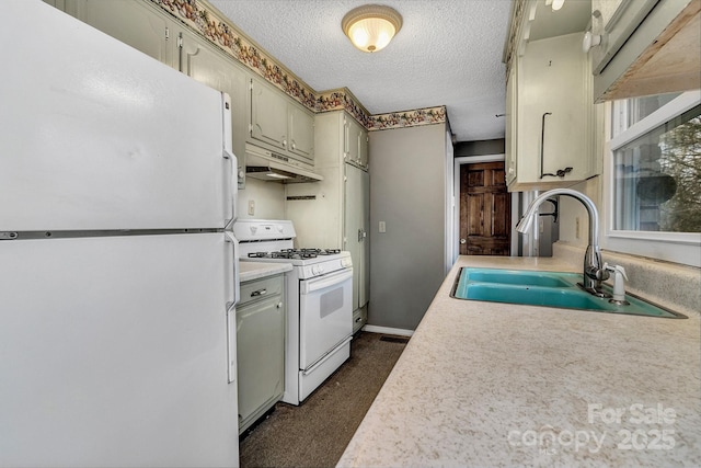 kitchen featuring under cabinet range hood, light countertops, white appliances, a textured ceiling, and a sink