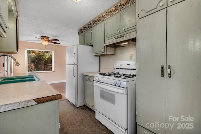 kitchen with a ceiling fan, under cabinet range hood, a sink, a textured ceiling, and white appliances