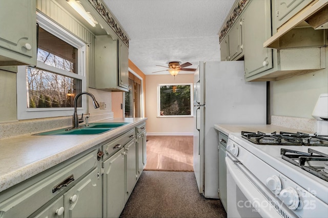 kitchen featuring white range with gas cooktop, ceiling fan, a sink, light countertops, and under cabinet range hood