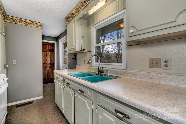 kitchen with a sink, baseboards, light countertops, a textured ceiling, and range