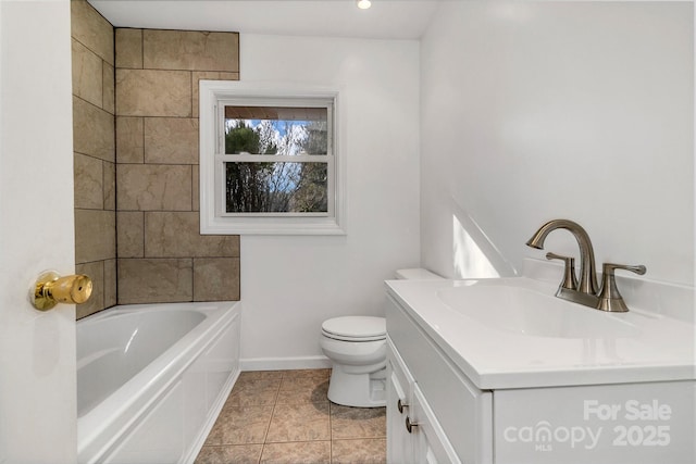 bathroom featuring baseboards, a washtub, toilet, tile patterned floors, and vanity