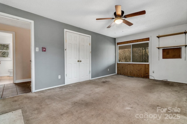 unfurnished bedroom featuring ceiling fan, baseboards, carpet floors, a closet, and a textured ceiling