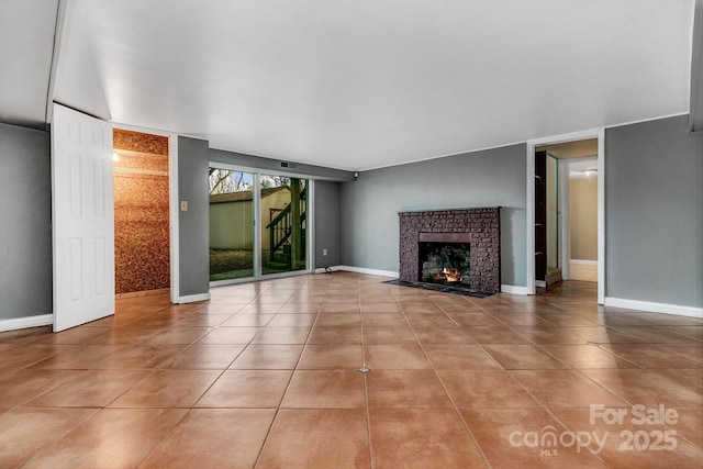 unfurnished living room featuring tile patterned floors, baseboards, and a warm lit fireplace