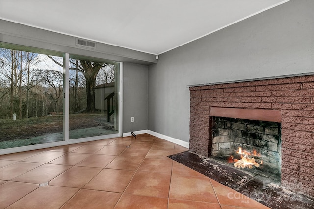 unfurnished living room featuring tile patterned floors, a brick fireplace, baseboards, and visible vents