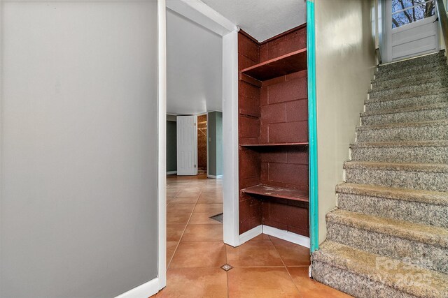 stairway with tile patterned floors and baseboards