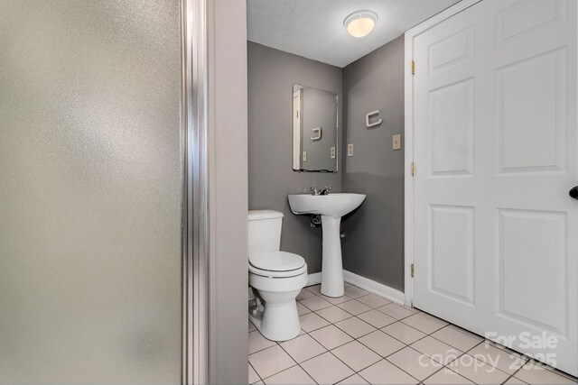 bathroom with tile patterned floors, toilet, baseboards, and a sink