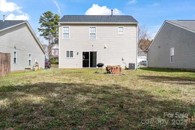 rear view of property with a yard, cooling unit, and fence