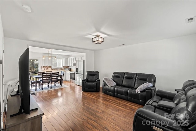 living area with visible vents and wood finished floors