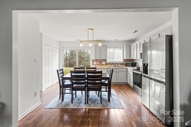 dining room with dark wood-style flooring, visible vents, and baseboards