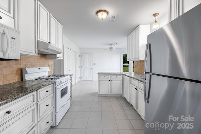 kitchen with white appliances, light tile patterned flooring, under cabinet range hood, white cabinetry, and backsplash