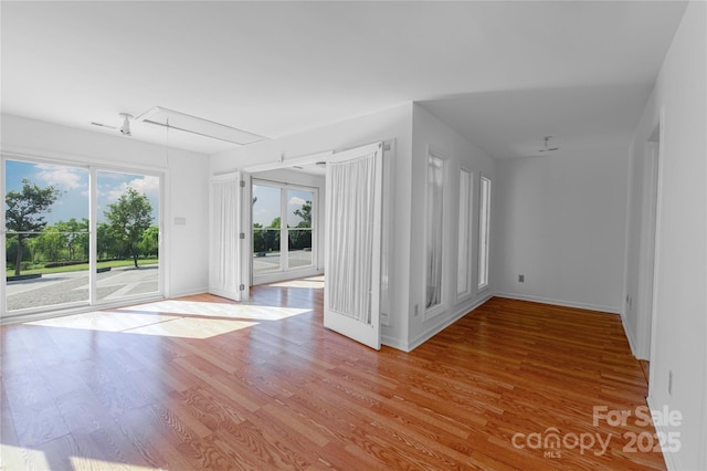 spare room featuring baseboards, attic access, and light wood-style flooring