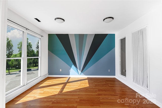 spare room featuring lofted ceiling, wood finished floors, and baseboards