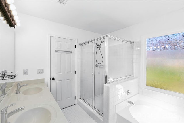 bathroom with tile patterned flooring, a bath, a stall shower, and a sink