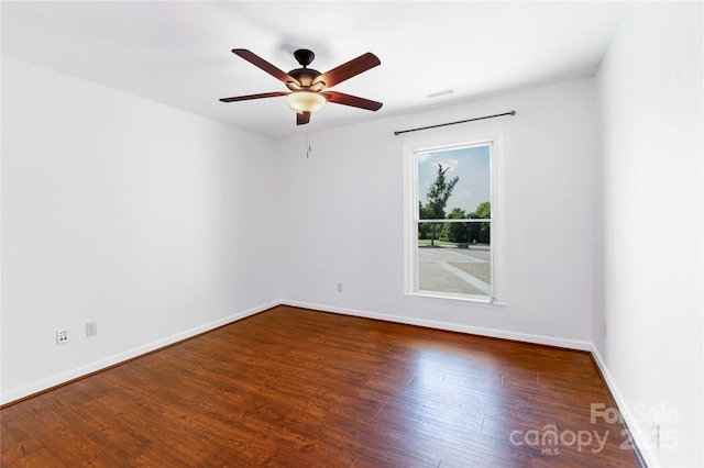 spare room with a ceiling fan, wood finished floors, visible vents, and baseboards