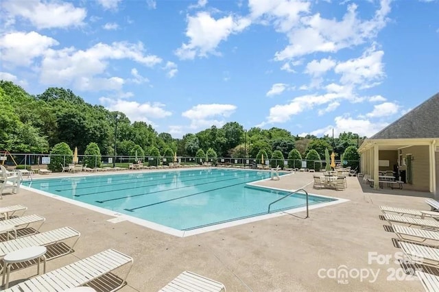 community pool with a patio and fence