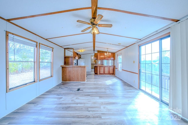 unfurnished living room with light wood-type flooring, vaulted ceiling, and ceiling fan with notable chandelier